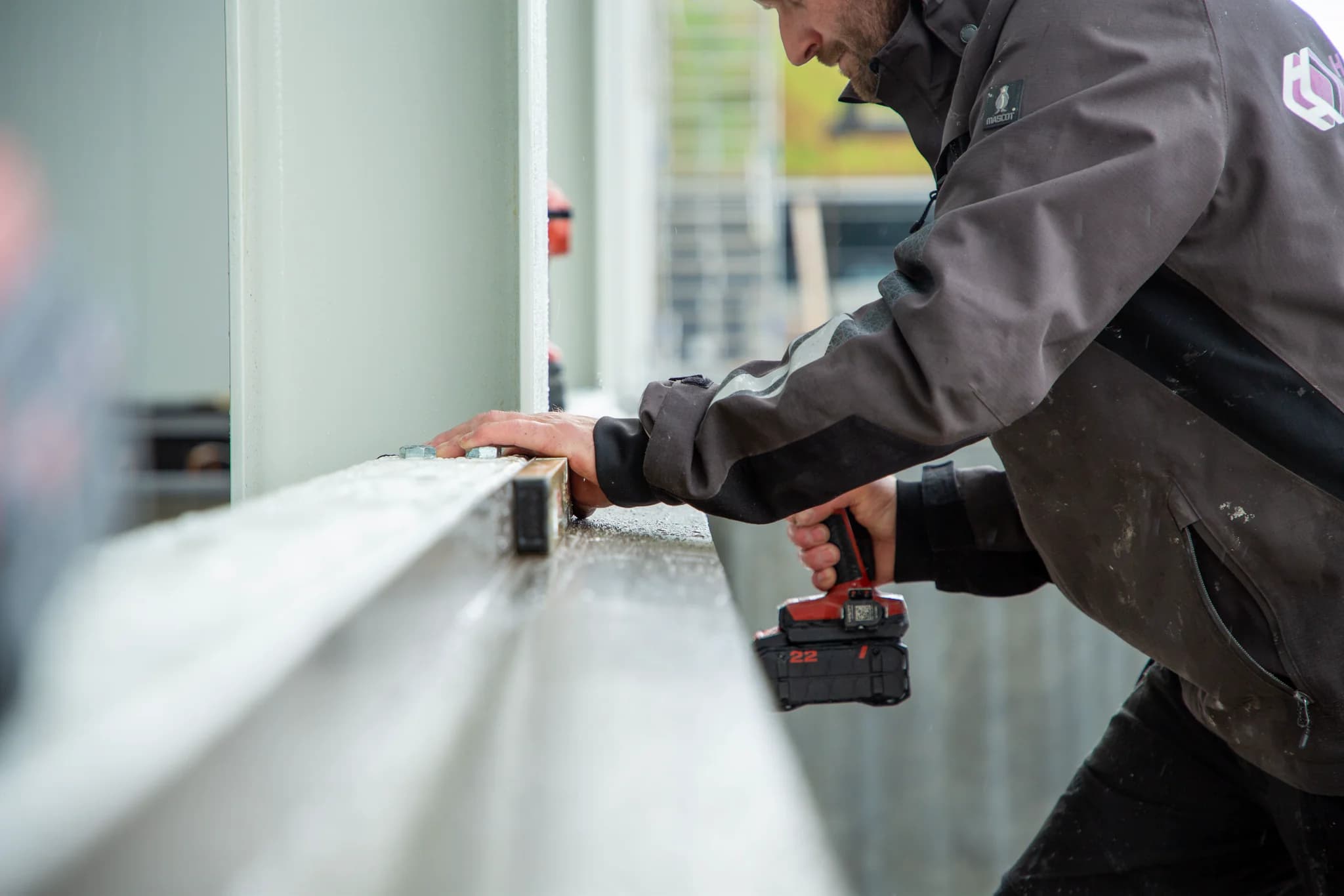 Monteur bevestigt gevelbekleding met een accuschroefmachine.