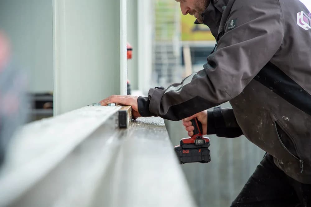 Monteur bevestigt gevelbekleding met een accuschroefmachine.