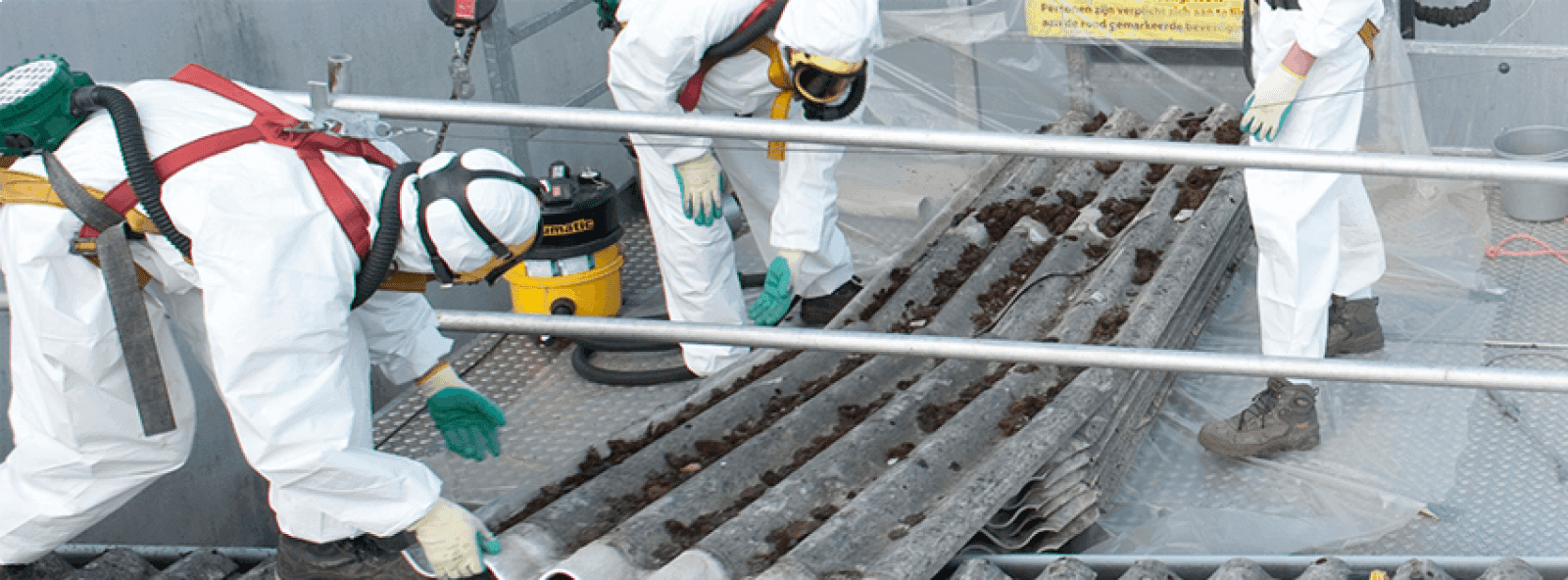 Gecertificeerde medewerkers verwijderen asbesthoudende dakplaten tijdens dakrenovatie